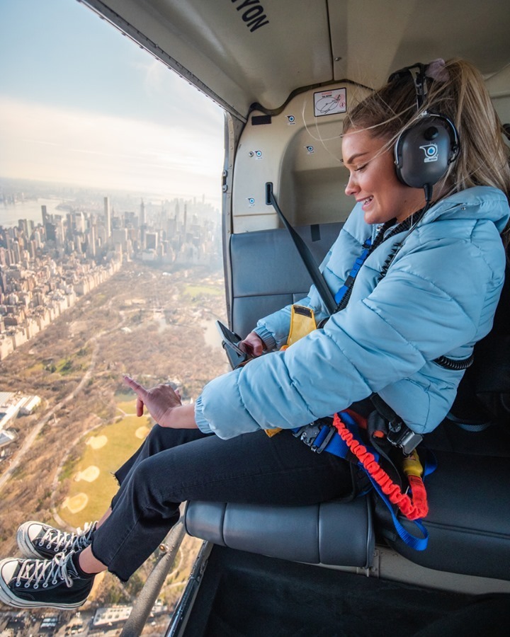 Girl taking photo on a FlyNYON doors off flight