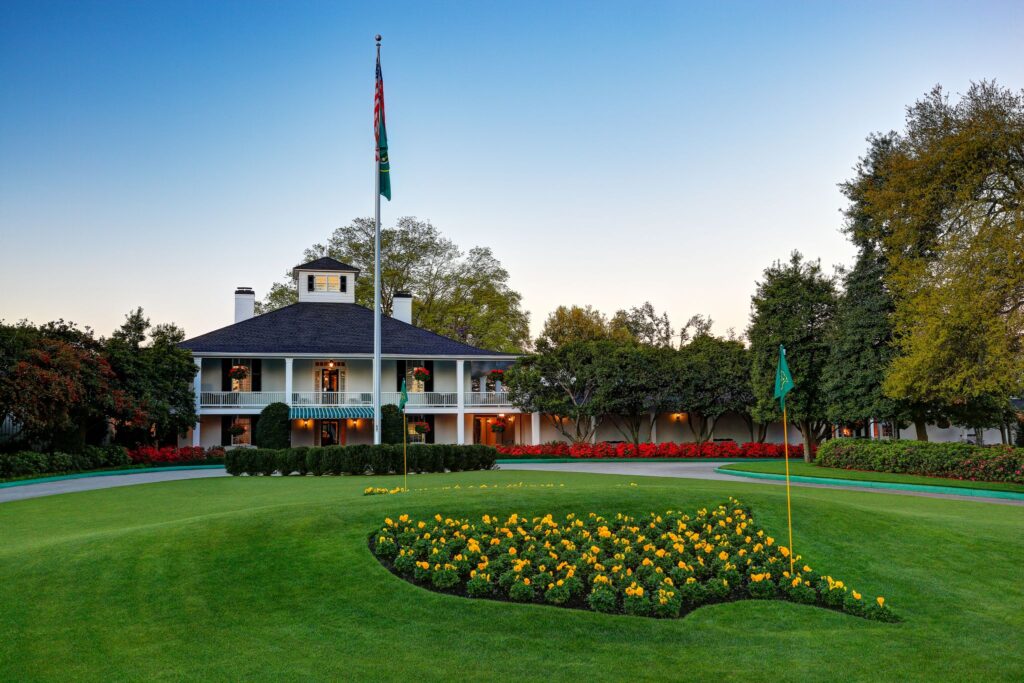 An image showcasing the main entrance of the nationally renowned Masters Golf Course in Augusta. The entrance is marked by its iconic, meticulously landscaped beauty.