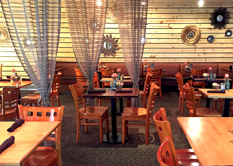 A photograph of the interior of a wooden-furnished restaurant featuring tables and chairs.