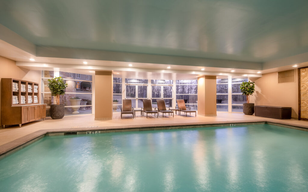 A pool in a wellness spa with big windows overseening the outdoors