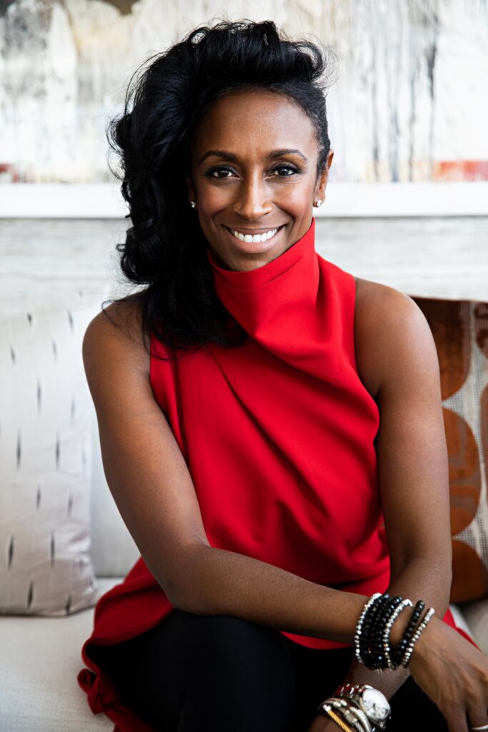 A woman (Kesha Franklin) dressed in a red blouse and black slacks
