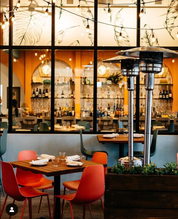 A photo of the interior and exterior of a beautiful restaurant's dining area over looking a bar