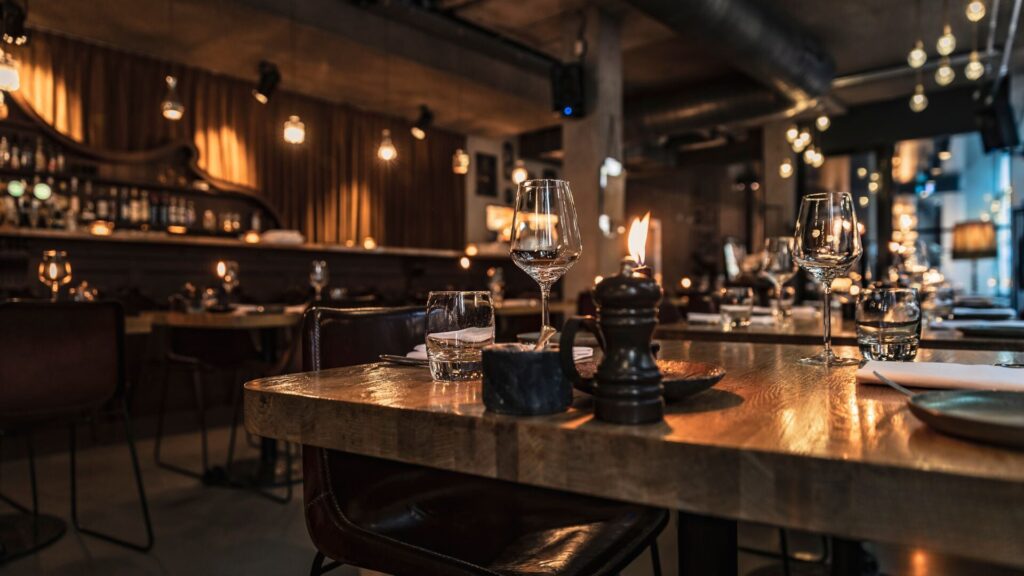 An image capturing the exquisite interior of a restaurant, where rustic wooden tables are illuminated by elegant lighting.