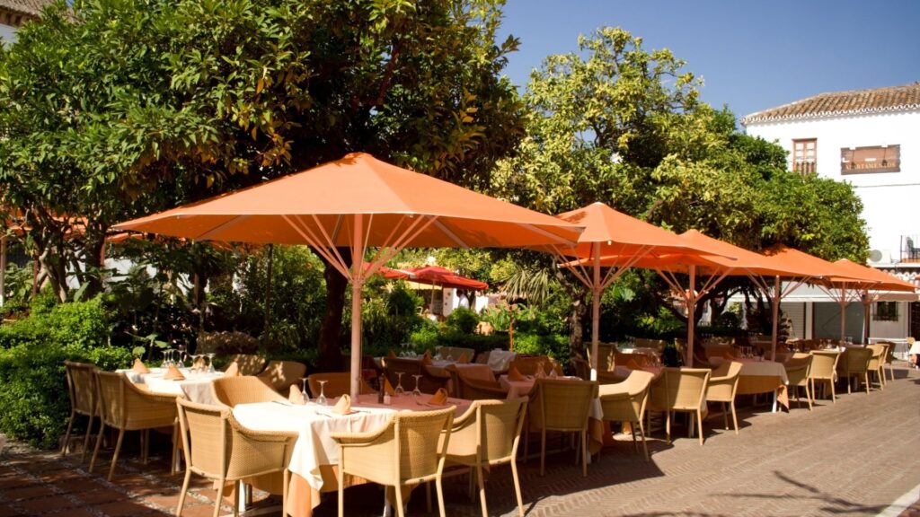 A photo displaying the charming outdoor seating area of a restaurant, where tables are comfortably shaded by vibrant orange umbrellas