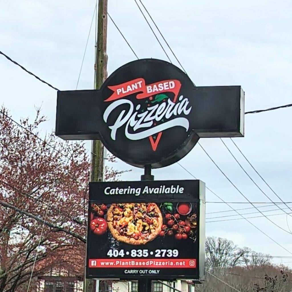 The image shows vibrant and inviting signage for a pizzeria, with bold, colorful letters spelling out 'Plant Based Pizzeria