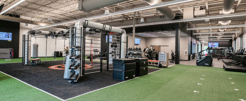 A warehouse-style looking gym with fitness equipment and cardio machines.