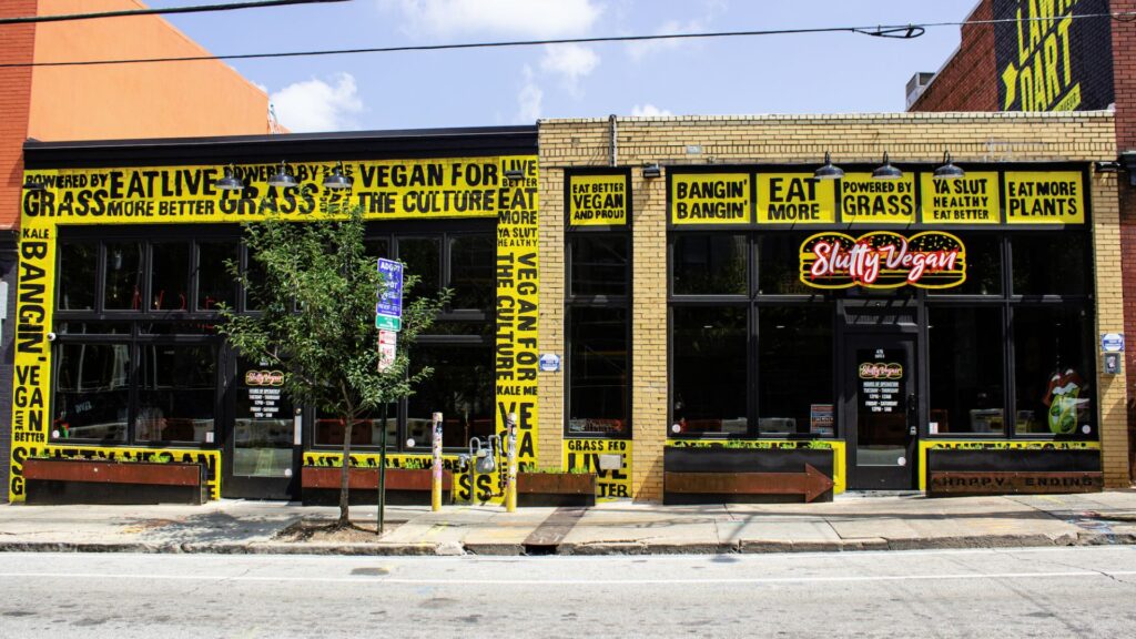A picture that depicts the outside of a restaurant with yellow graphics on a brick facade