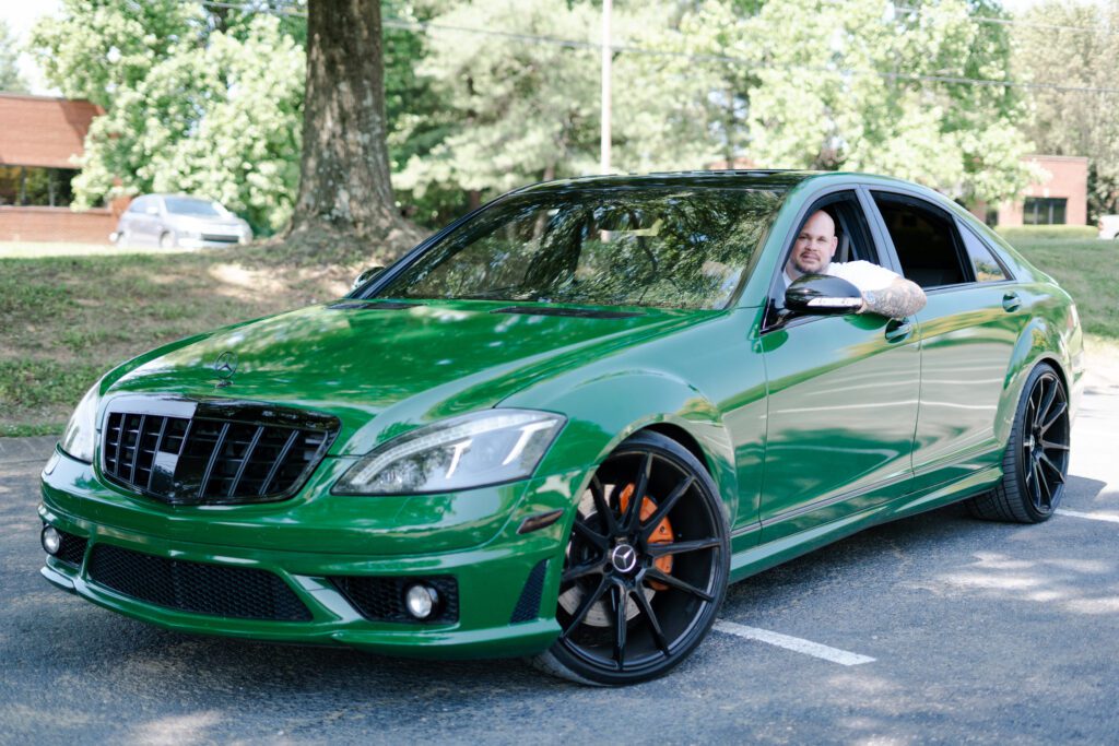 Rich behind the wheel of a custom green Mercedes — a symbol of Elite Customs’ drive to merge power and personality.