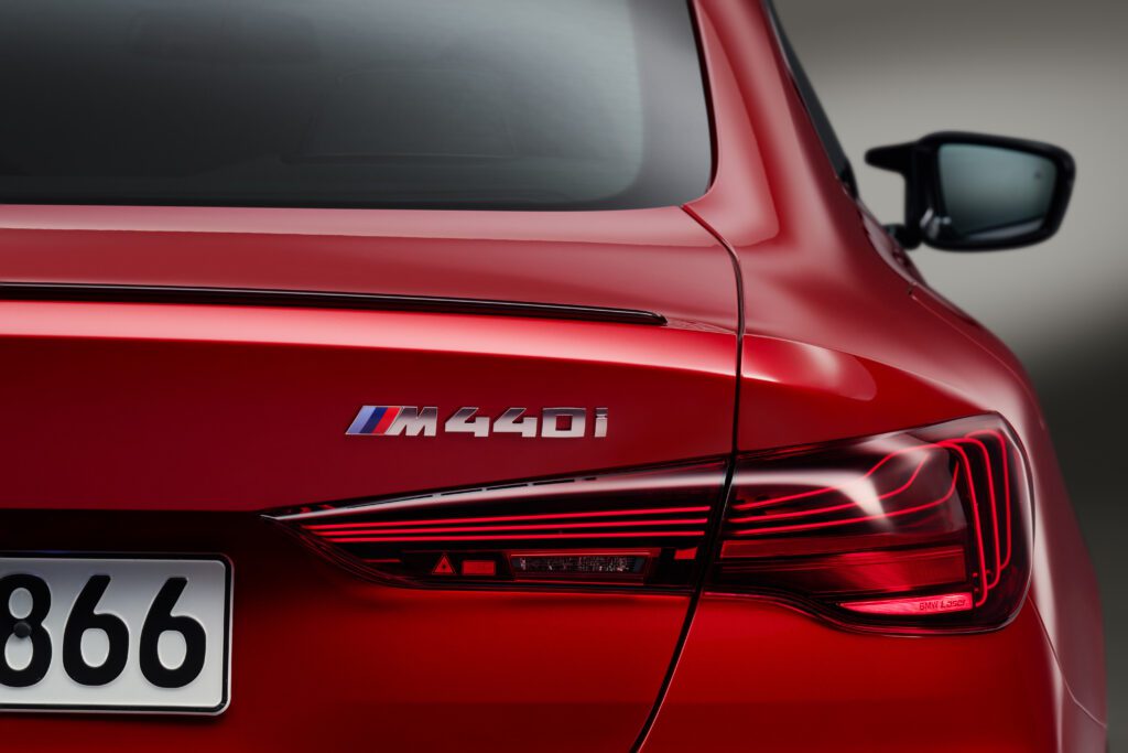 Rear detail of the 2025 BMW M440i in red with bold badging and taillight contour