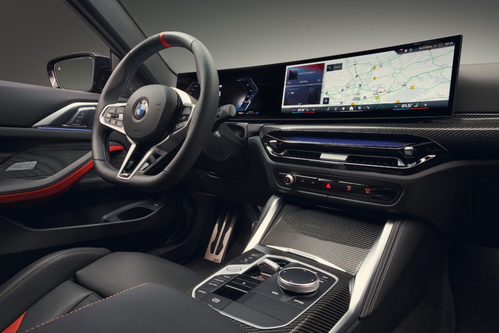 Close-up angle of the 2025 BMW M440i cockpit showcasing the iDrive system and ambient lighting