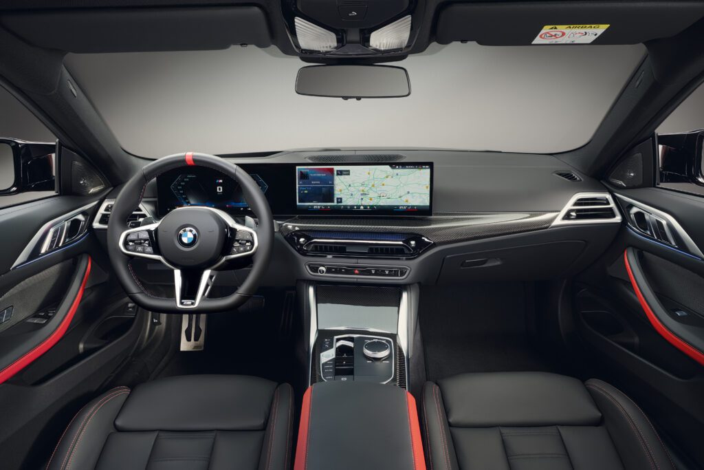 Interior of the 2025 BMW M440i featuring black Vernasca leather, red accents, and a widescreen display