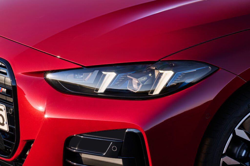 Close-up of the 2025 BMW M440i front headlight in red, showcasing signature lighting and aerodynamic styling