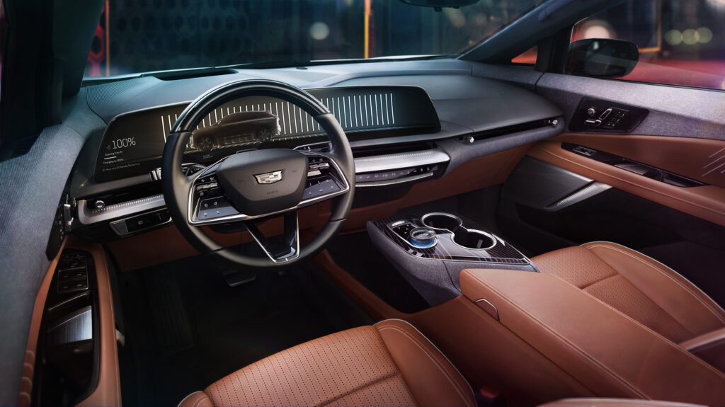 Full front cabin view of the Cadillac OPTIQ in two-tone brown and black, highlighting the minimalist dash and premium finish.