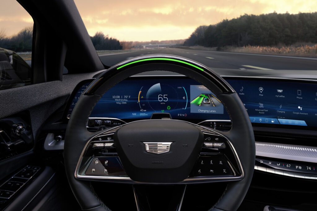 Steering wheel with illuminated green Super Cruise indicator and digital speed display, captured during highway driving.