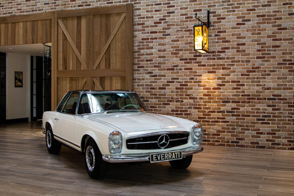 Side view of Everrati's Electric Classic Car white Mercedes-Benz Pagoda in a modern, rustic interior.