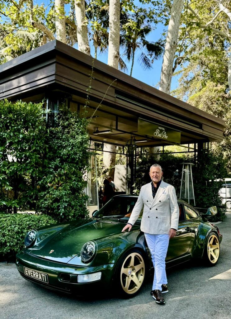 Justin Lunny, Founder & CEO of Everrati, poses beside a forest green electric Porsche 911 outside Hotel Bel-Air, reflecting the brand’s blend of classic automotive design and modern EV innovation.